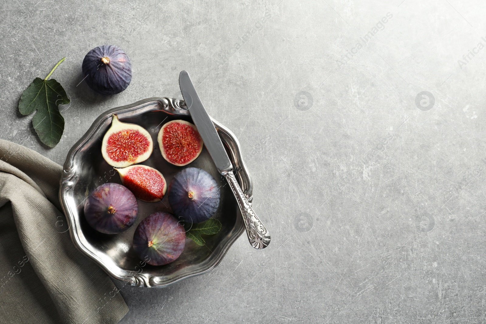 Photo of Dish with fresh ripe figs on gray background, top view. Space for text