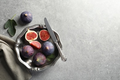 Photo of Dish with fresh ripe figs on gray background, top view. Space for text