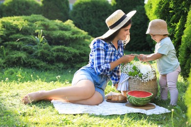 Mother with her baby daughter having picnic in garden on sunny day