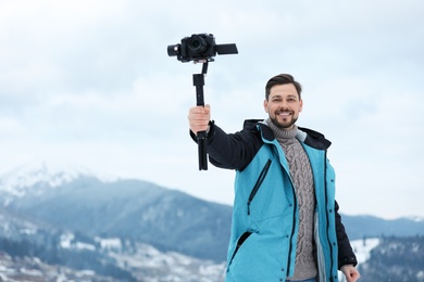 Man with stabilizer and camera recording video in mountains. Winter vacation