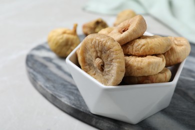 Tasty dried figs in bowl on light grey table, closeup