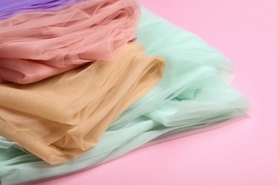 Photo of Beautiful colorful tulle fabrics on pink background, closeup