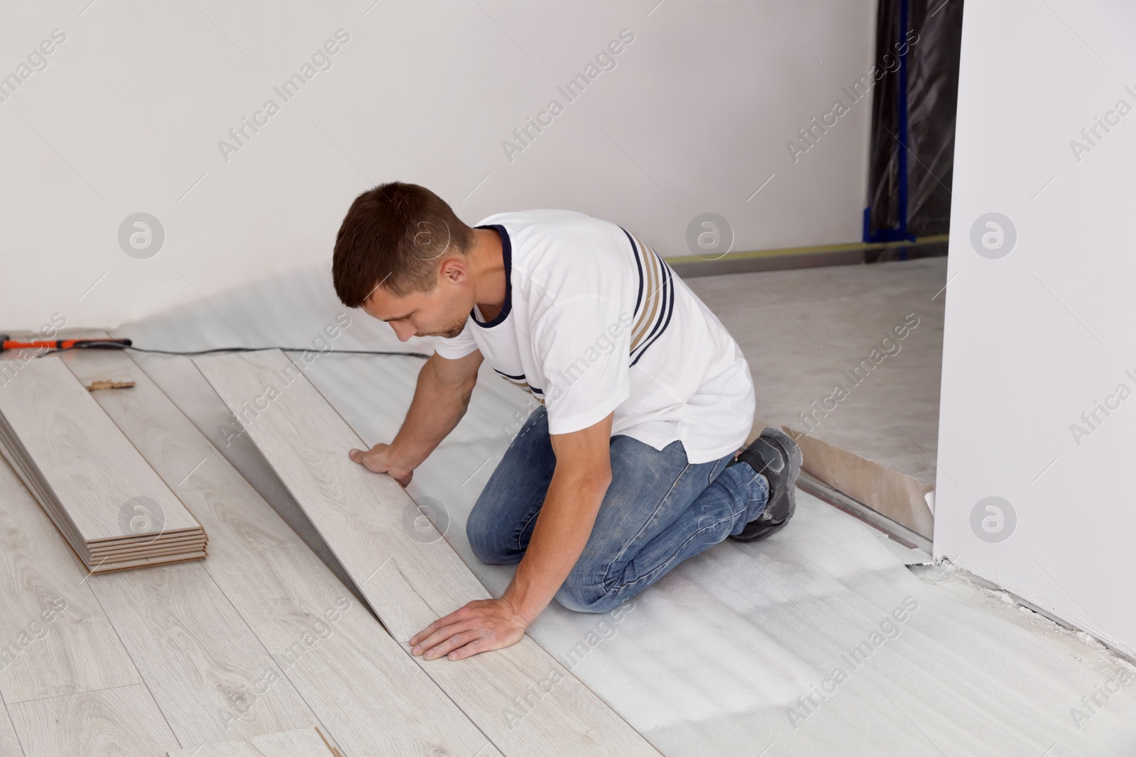 Photo of Man installing new laminate flooring in room