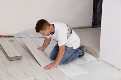 Man installing new laminate flooring in room