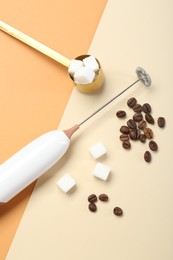 Milk frother wand, coffee beans and sugar cubes on color background, flat lay