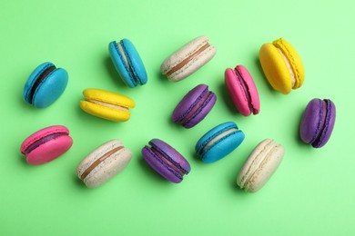 Photo of Delicious colorful macarons on green background, flat lay