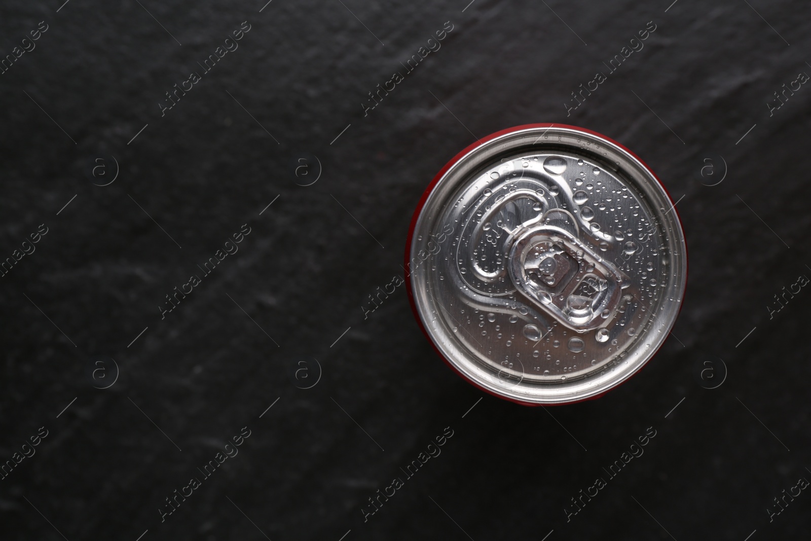 Photo of Energy drink in wet can on black textured background, top view. Space for text