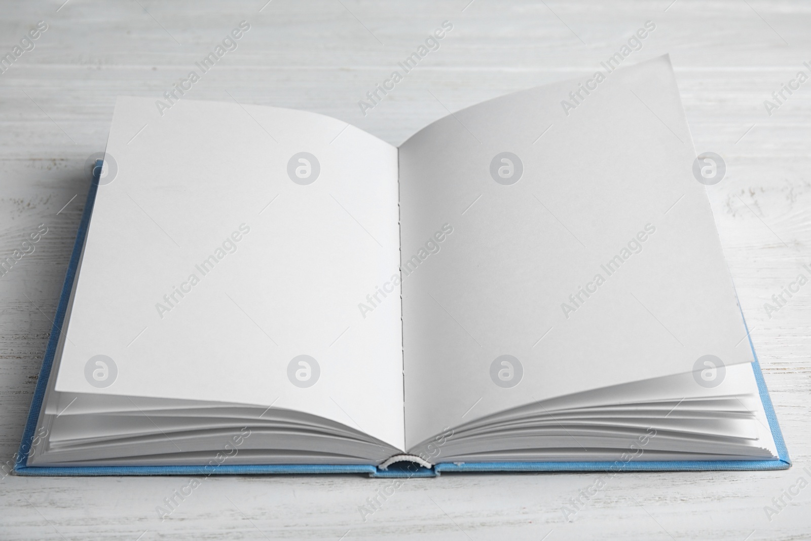 Photo of Open book on white wooden table. Space for text