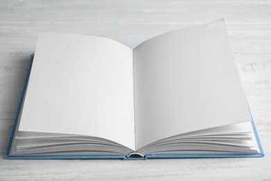 Photo of Open book on white wooden table. Space for text