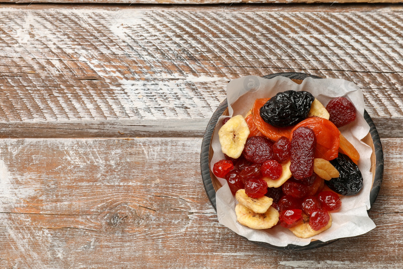 Photo of Mix of delicious dried fruits on wooden table, top view. Space for text