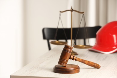 Photo of Law concept. Gavel, scales and red hard hat on white wooden table, space for text