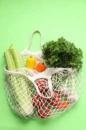 String bag with different vegetables on light green background, top view