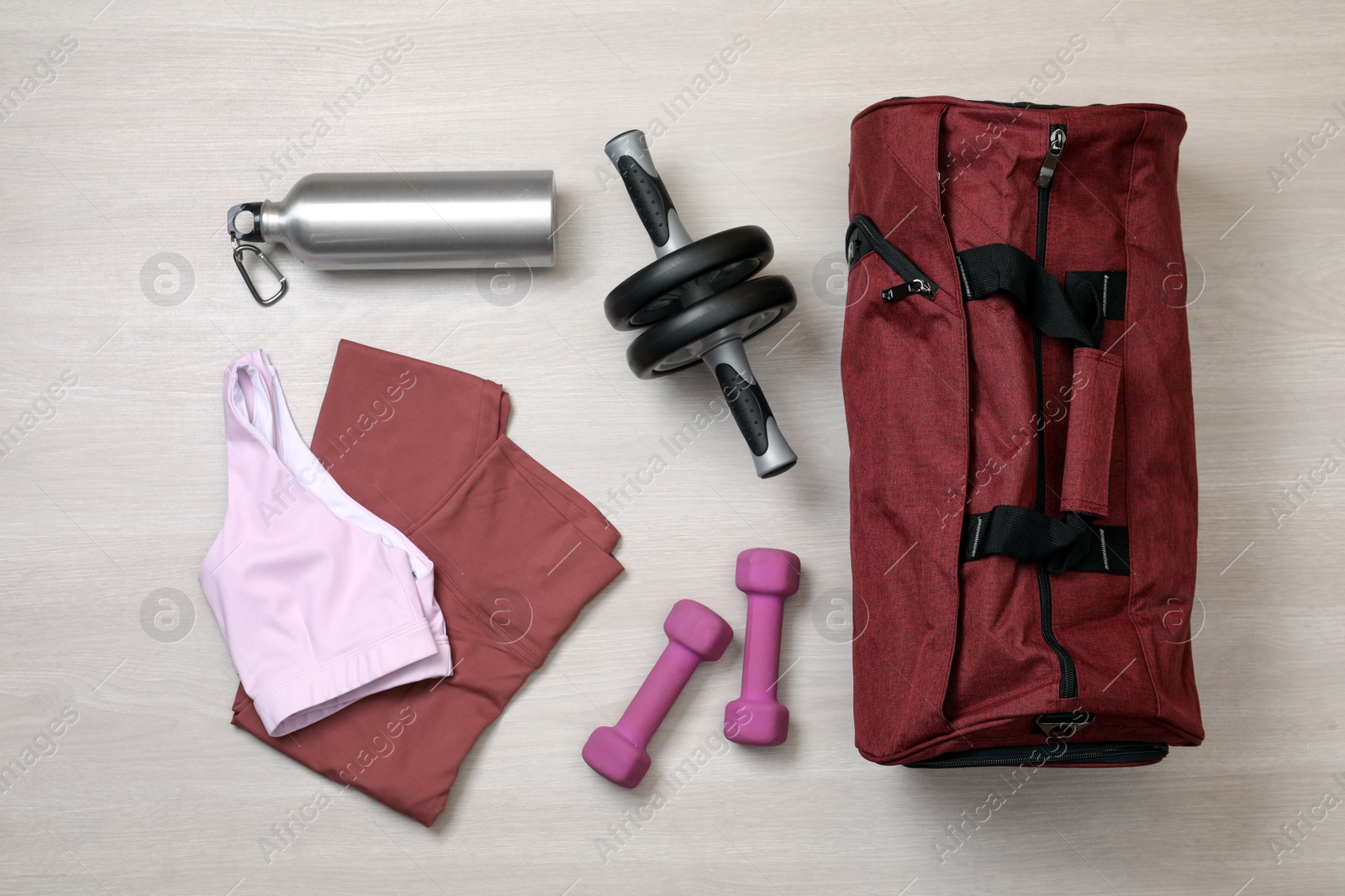 Photo of Gym bag and sports equipment on wooden background, flat lay