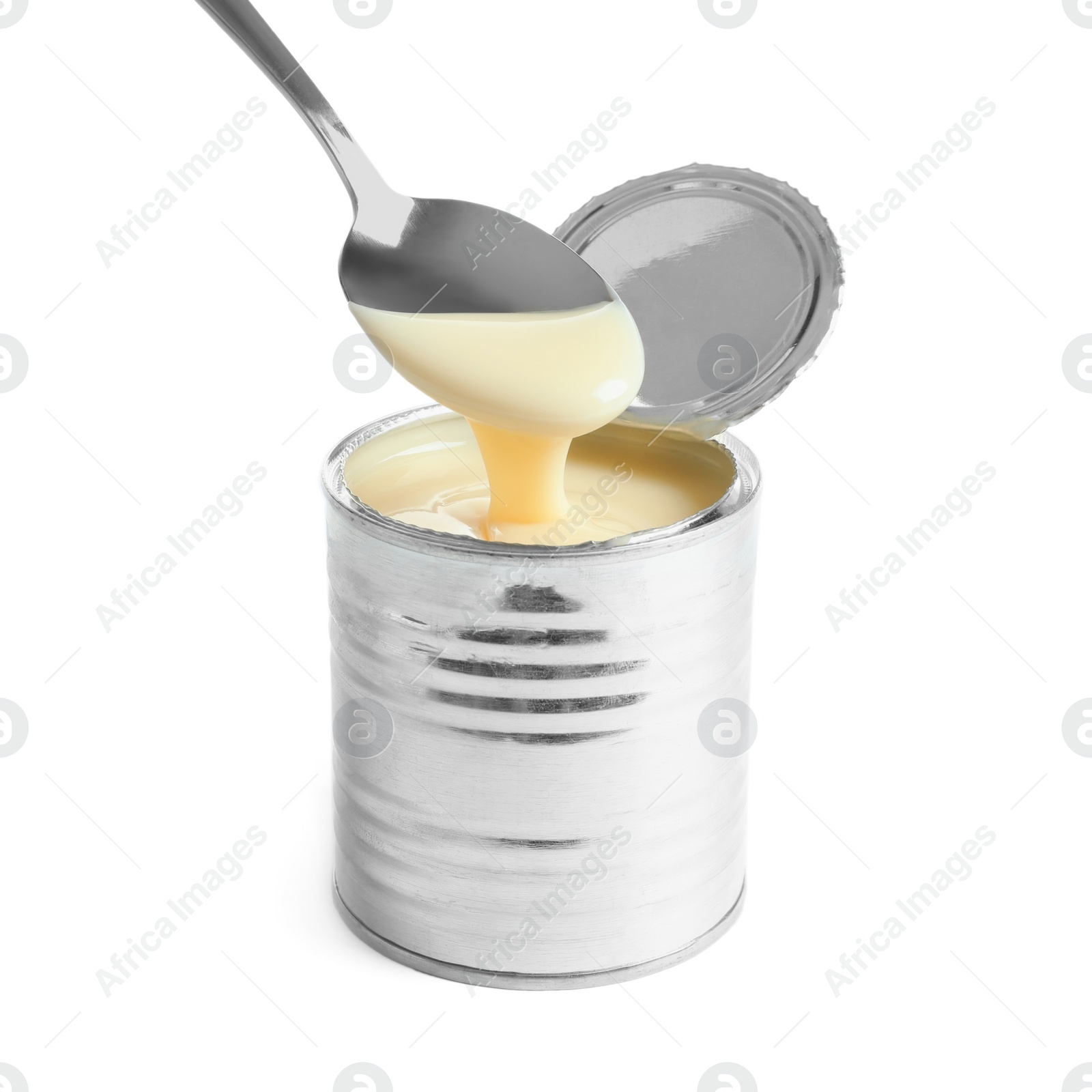 Photo of Condensed milk pouring from spoon into tin can on white background. Dairy product