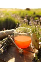 Photo of Jar of honey on wooden table in lavender field. Space for text