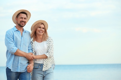 Happy romantic couple walking on beach, space for text