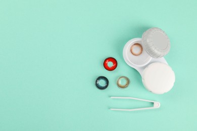 Different color contact lenses, tweezers and case on turquoise background, flat lay. Space for text