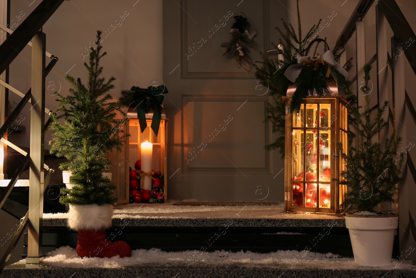 Photo of Decorative lanterns and small Christmas trees near house entrance