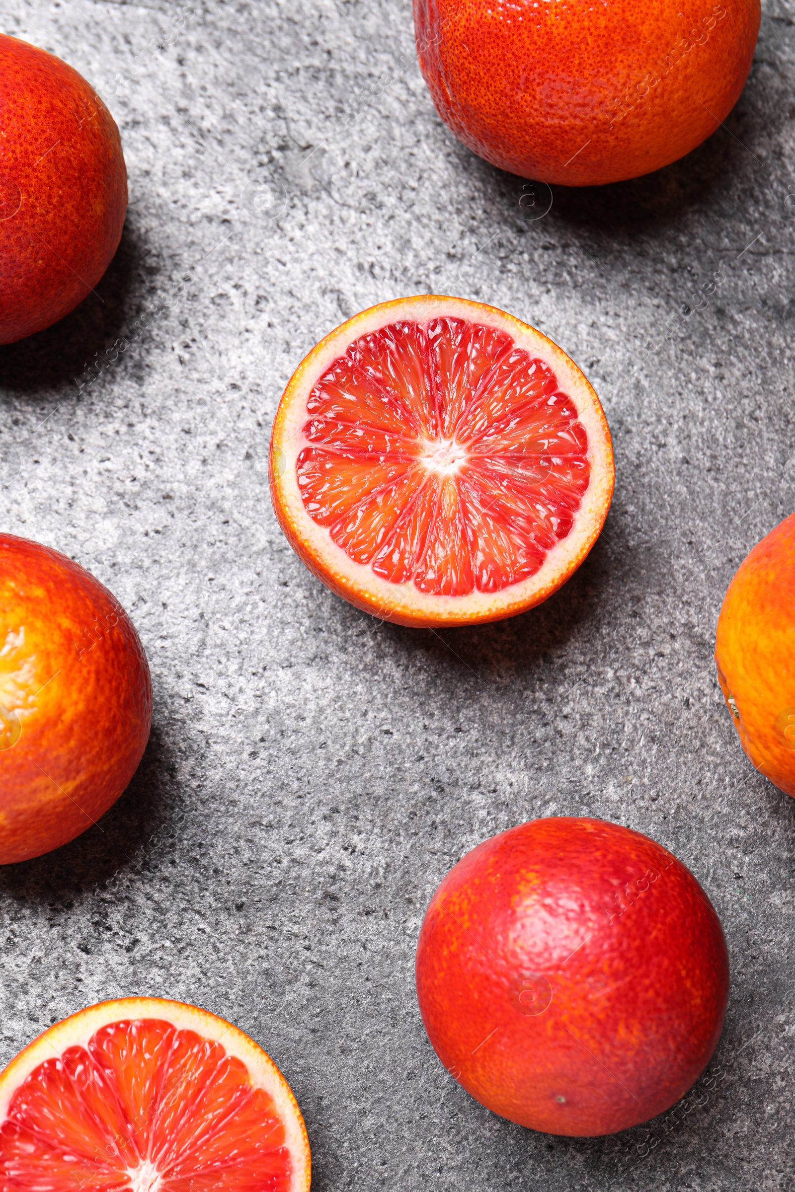 Photo of Whole and cut red oranges on grey table, flat lay