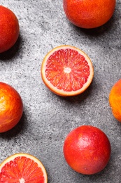 Whole and cut red oranges on grey table, flat lay