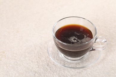 Delicious coffee in cup on light textured table, closeup. Space for text