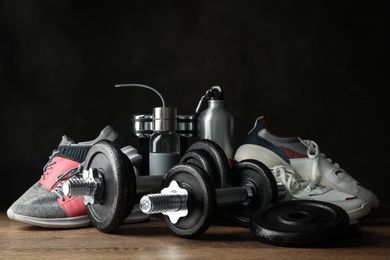 Photo of Gym equipment and accessories on wooden floor against dark background