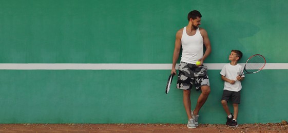 Image of Father with his son near green wall on tennis court. Banner design with space for text