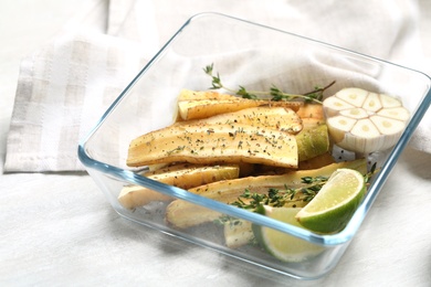 Photo of Raw cut white carrot with lime slices and garlic in baking dish on wooden table