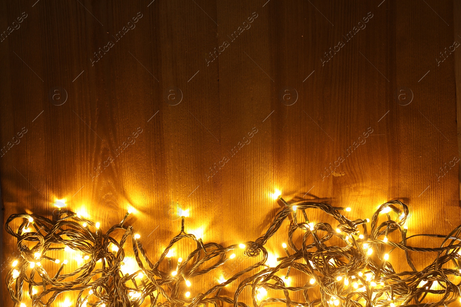 Photo of Beautiful bright Christmas lights on wooden background, flat lay. Space for text