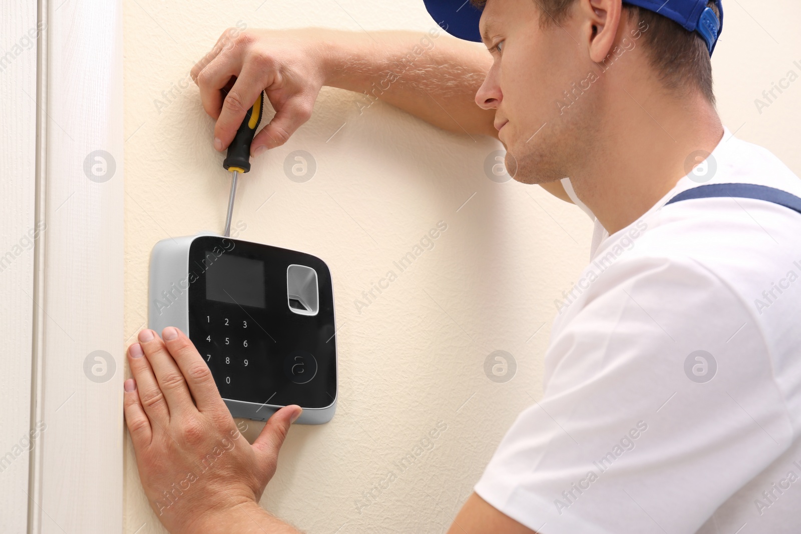 Photo of Male technician installing security alarm system indoors