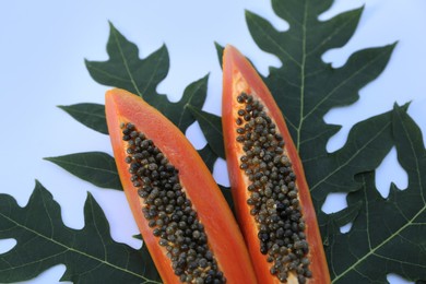 Fresh ripe papaya slices with leaf on white background, flat lay