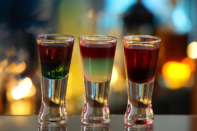 Photo of Different shooters in shot glasses on mirror surface against blurred background Alcohol drink