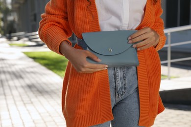 Young African American woman with stylish waist bag on city street, closeup