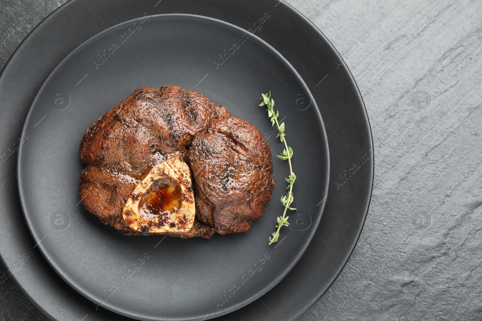 Photo of Tasty grilled beef meat and thyme on black table, top view