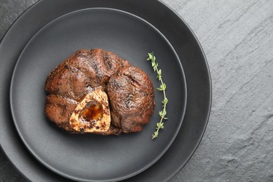 Tasty grilled beef meat and thyme on black table, top view