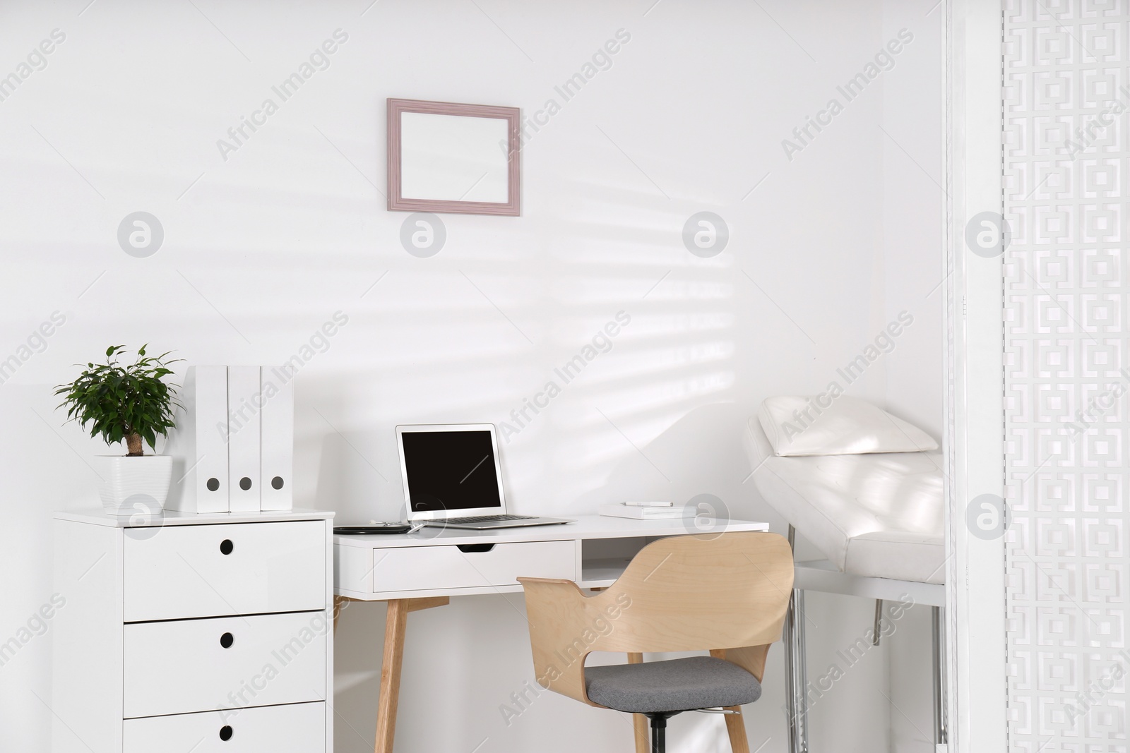 Photo of Doctor's office interior with examination couch and desk