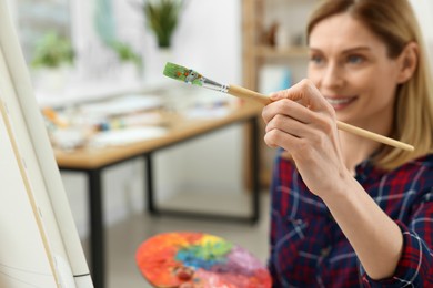 Woman painting on canvas in studio, selective focus. Creative hobby