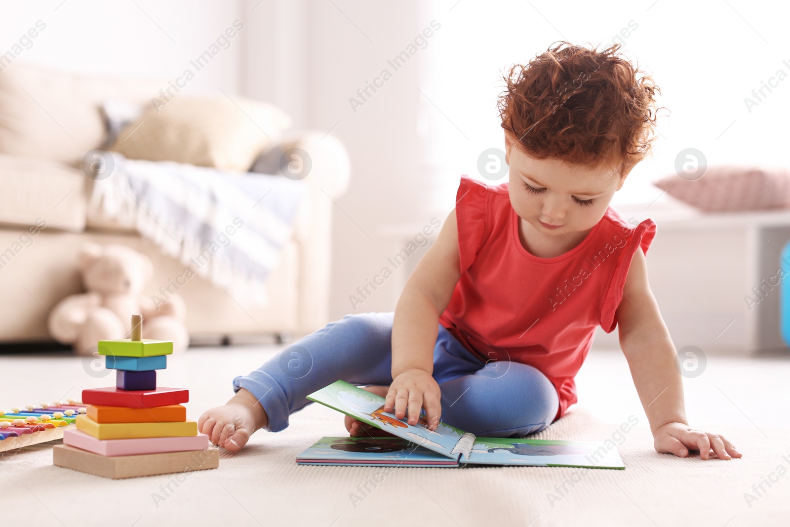 Photo of Cute little child playing with toys on floor at home