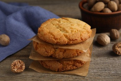 Tasty cookies and nutmeg seeds on wooden table, closeup