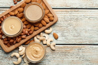 Photo of Different types of delicious nut butters and ingredients on light blue wooden table, flat lay. Space for text