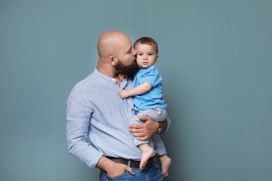 Portrait of dad and his little son on color background