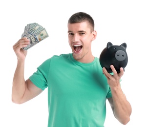 Handsome young man with dollars and piggy bank on white background