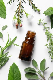 Bottle of essential oil and different herbs on white background, flat lay