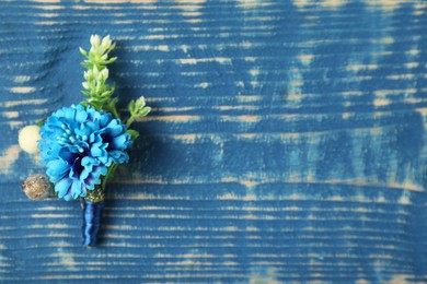 Photo of Stylish boutonnieres on blue wooden table, top view. Space for text