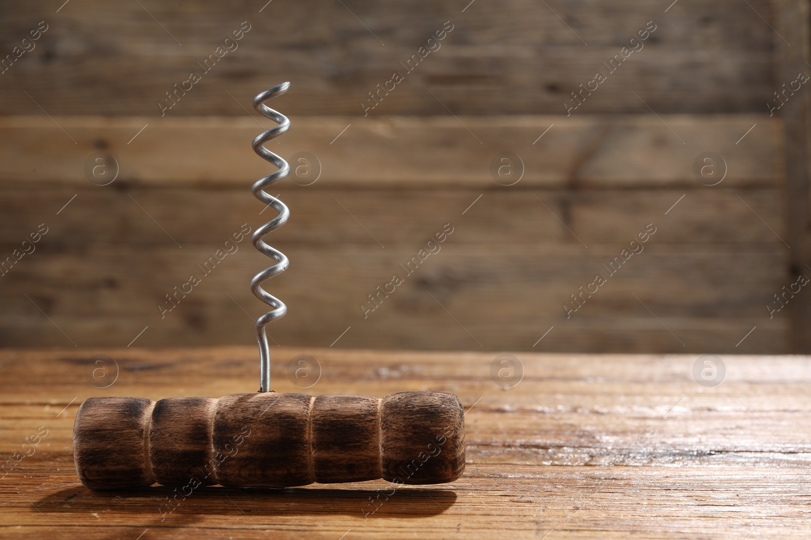 Photo of One corkscrew on wooden table, closeup. Space for text