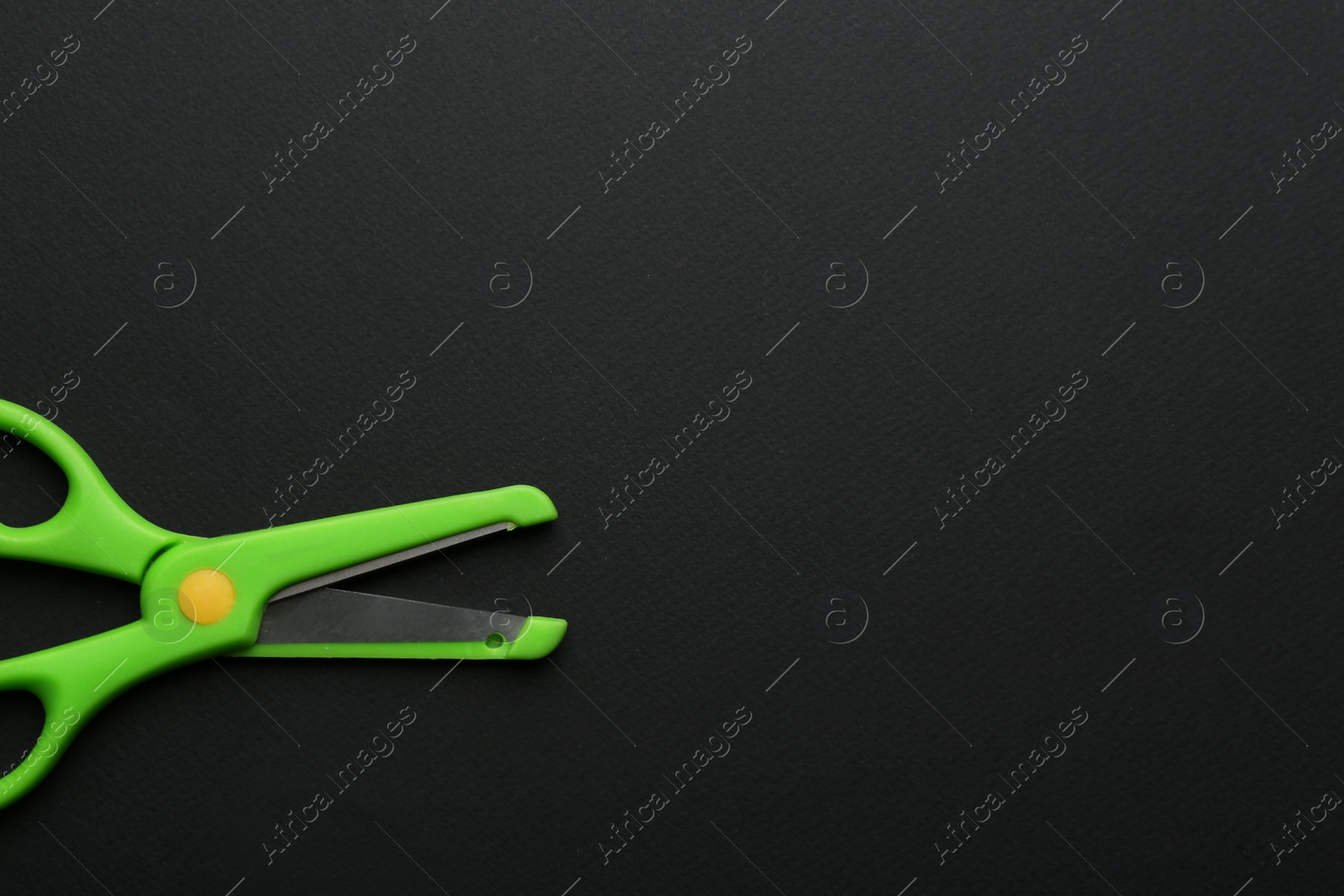 Photo of Pair of training scissors on dark background, top view. Space for text