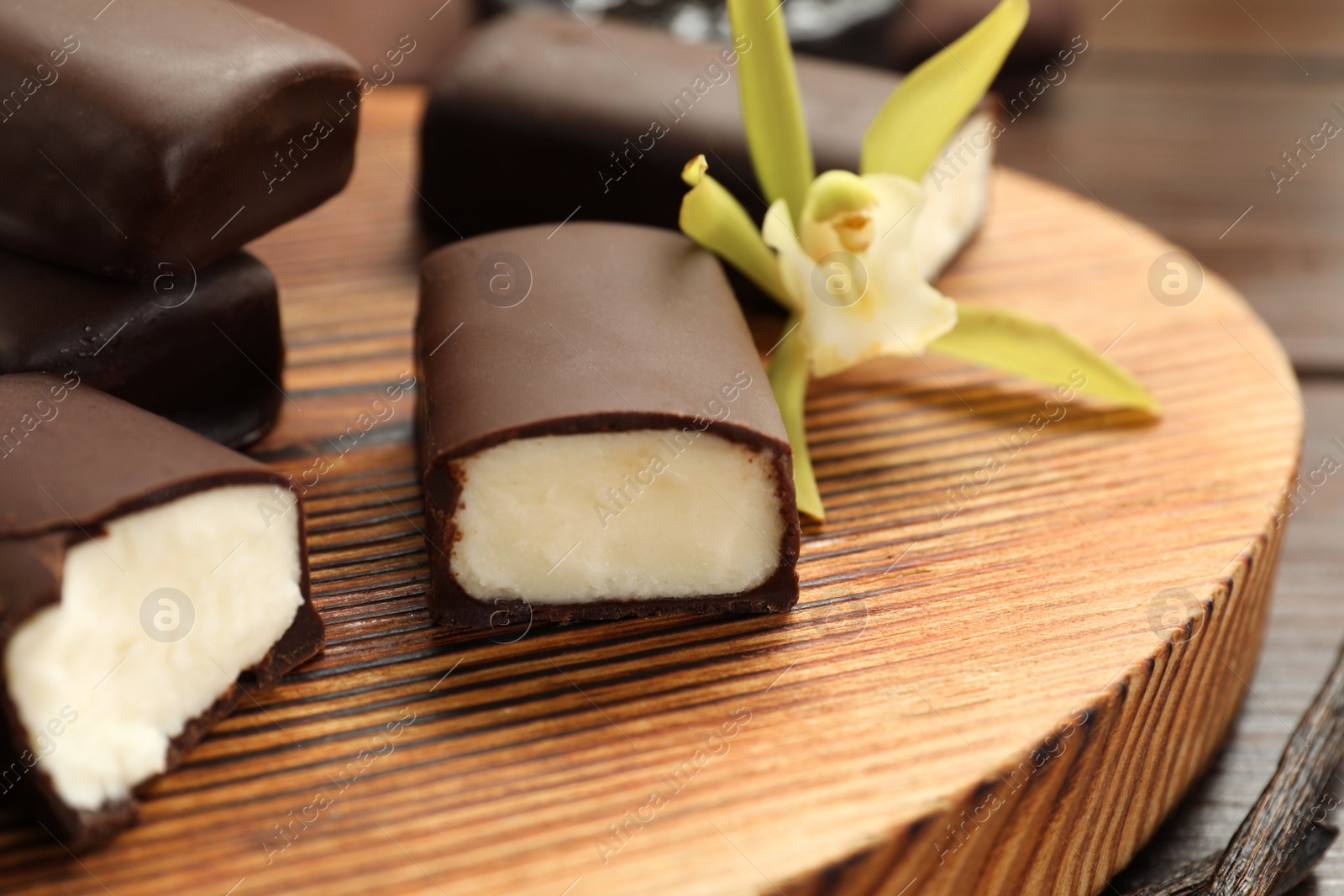 Photo of Glazed curd cheese bars and vanilla flower on wooden table, closeup