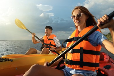 Couple in life jackets kayaking on river. Summer activity