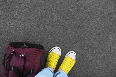 Photo of Woman with bag standing on asphalt, top view. Space for text