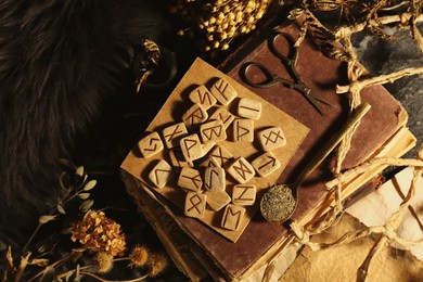 Photo of Many wooden runes, dried flowers and old books on altar, flat lay